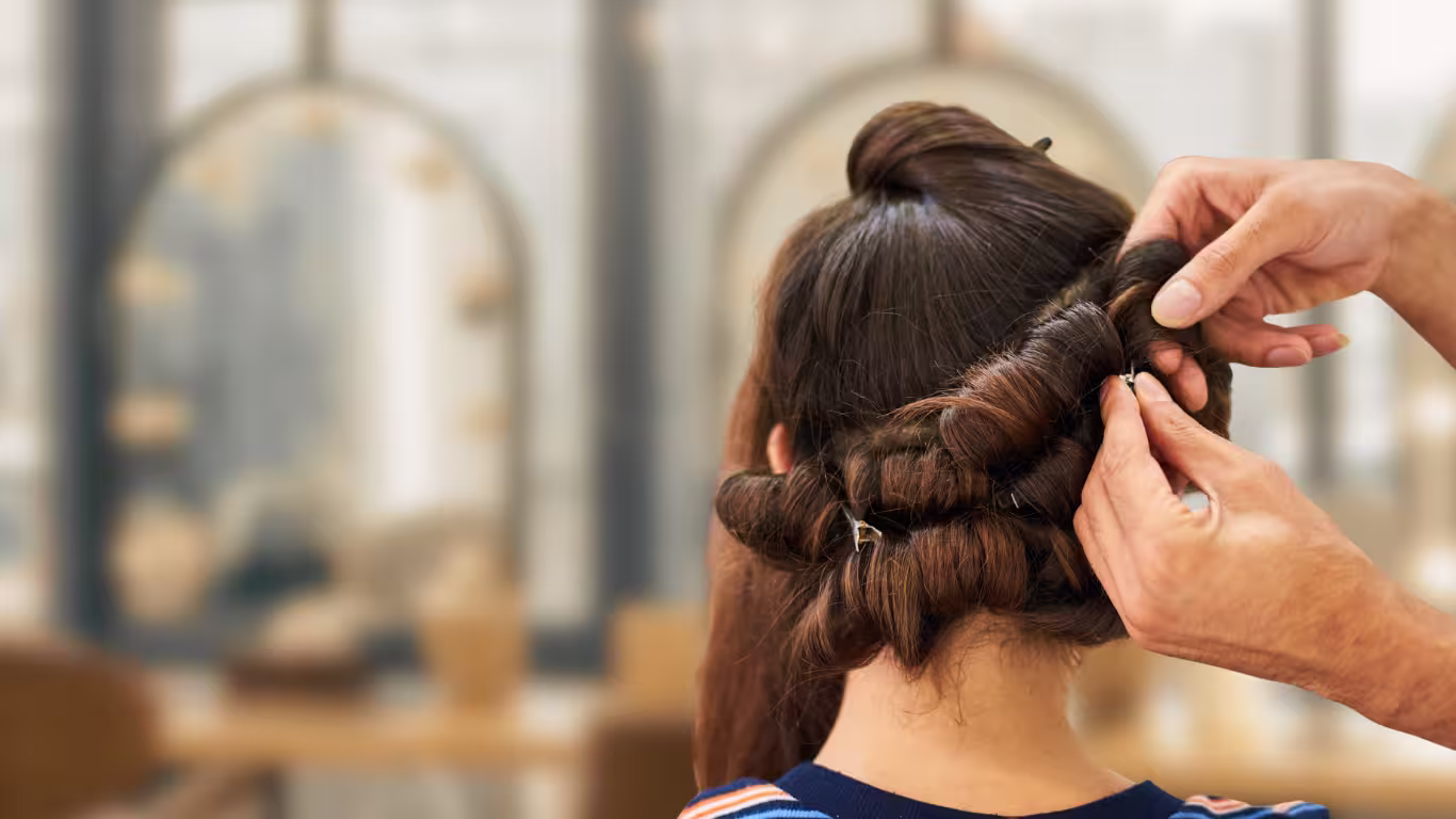 Hair stylist pinning curls into an elegant updo in a professional salon setting.