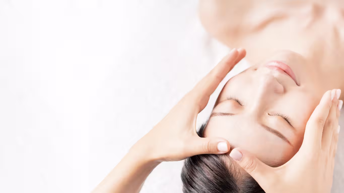 Young woman receiving gentle facial massage during skin care treatment at beauty academy.